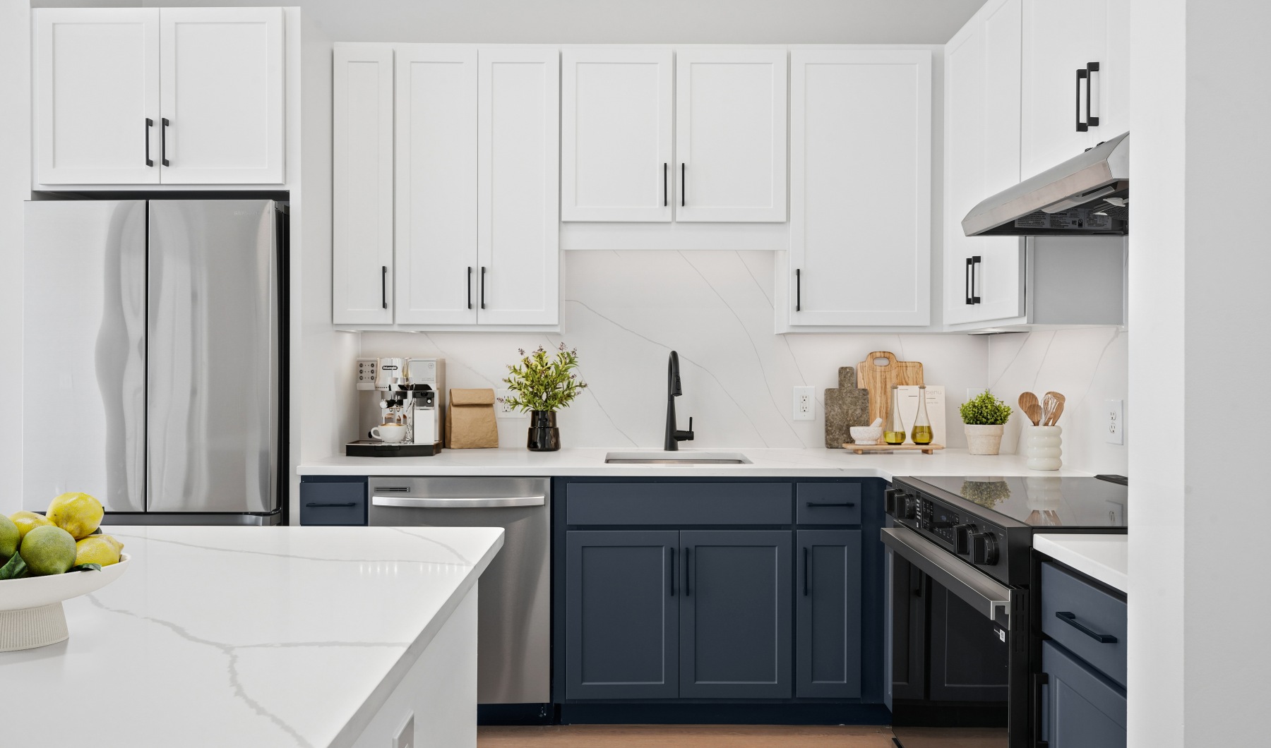 a newly renovated apartment with white and navy cabinets, black fixtures, and a white quartz kitchen island