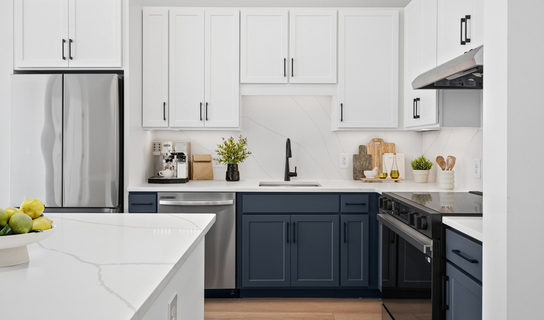 a newly renovated apartment with white and navy cabinets, black fixtures, and a white quartz kitchen island
