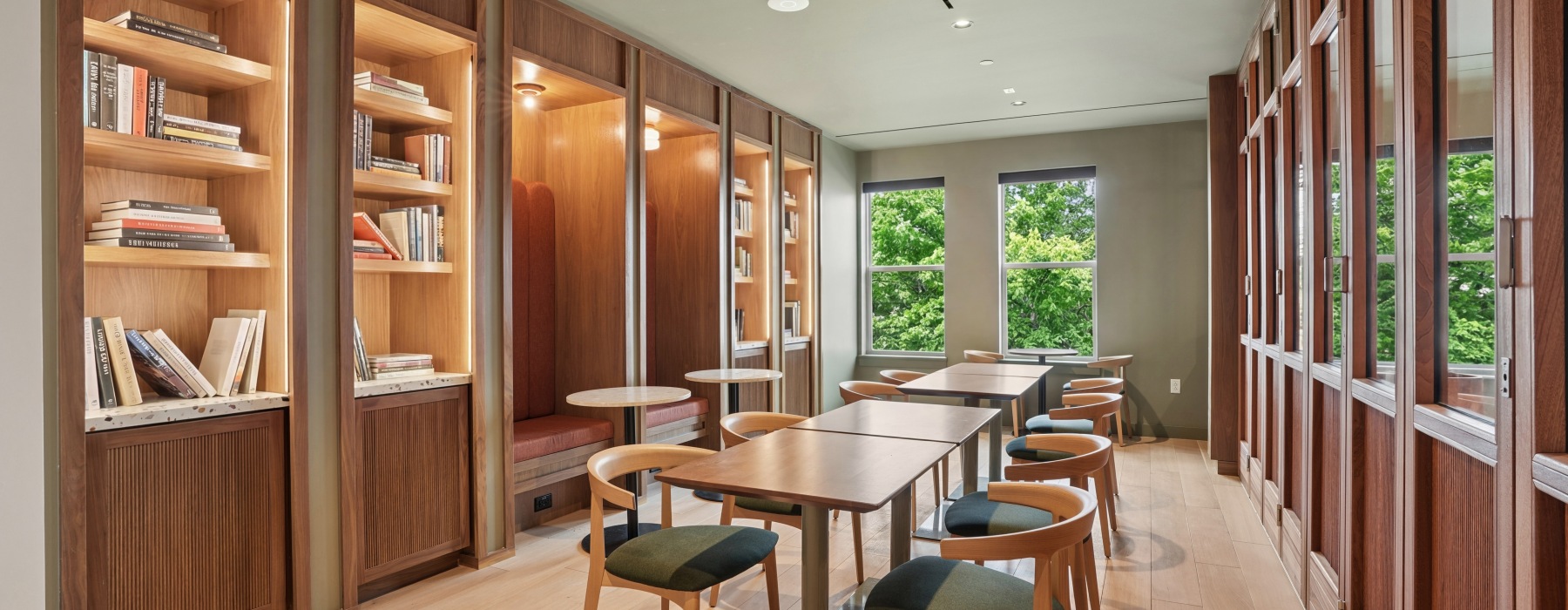 Library with shelves of books and a row of tables with chairs 